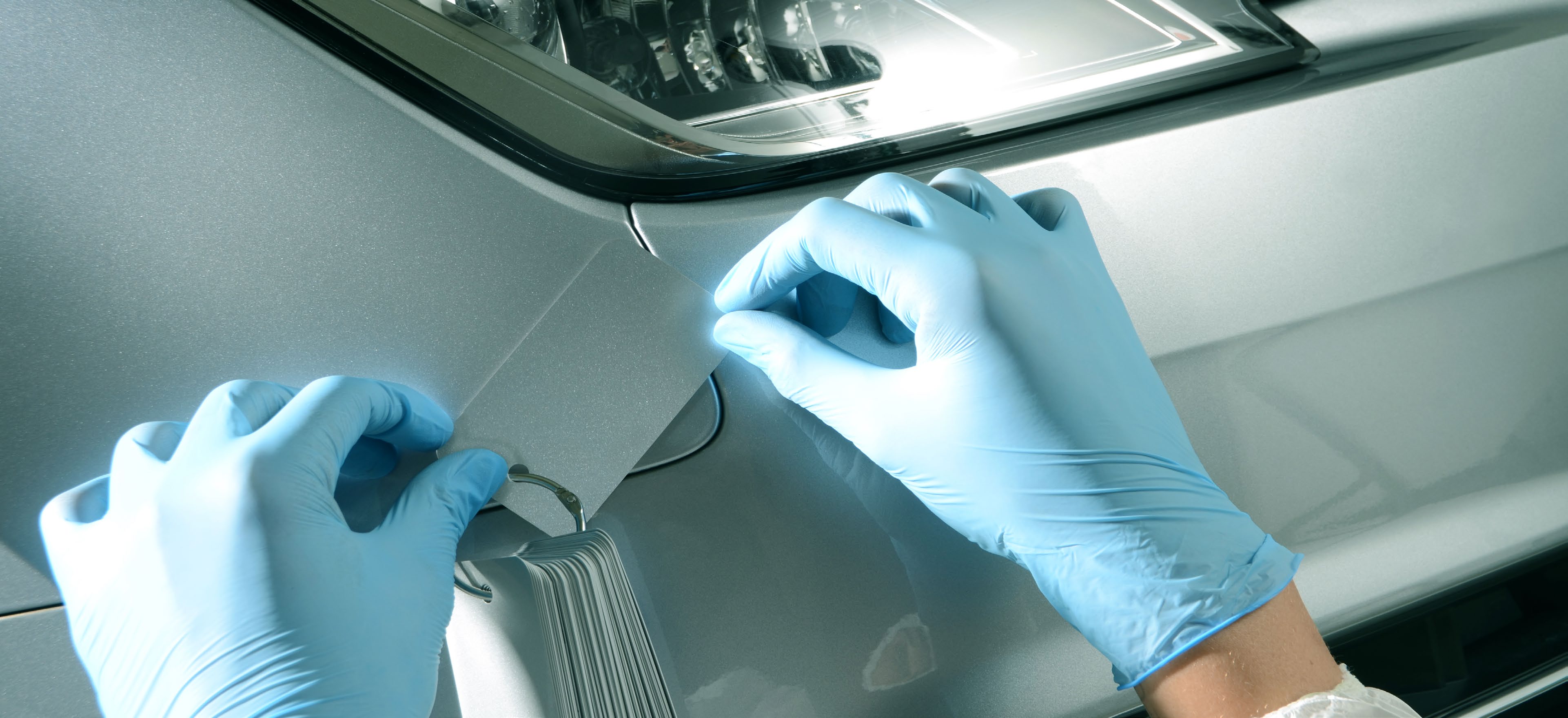 Technician holding an ARC colour swatch fan beside a vehicle interior